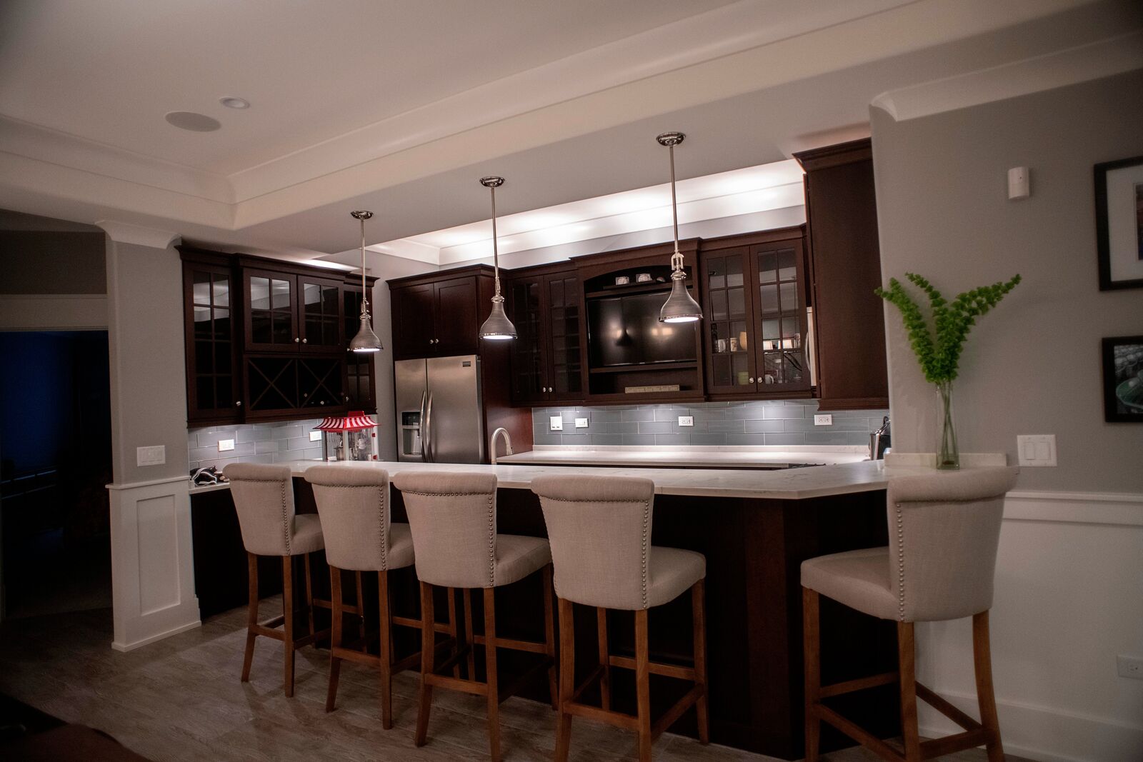 Lower level bar with dark stained cabinetry, glass fronts, a stone countertop and upholstered stools