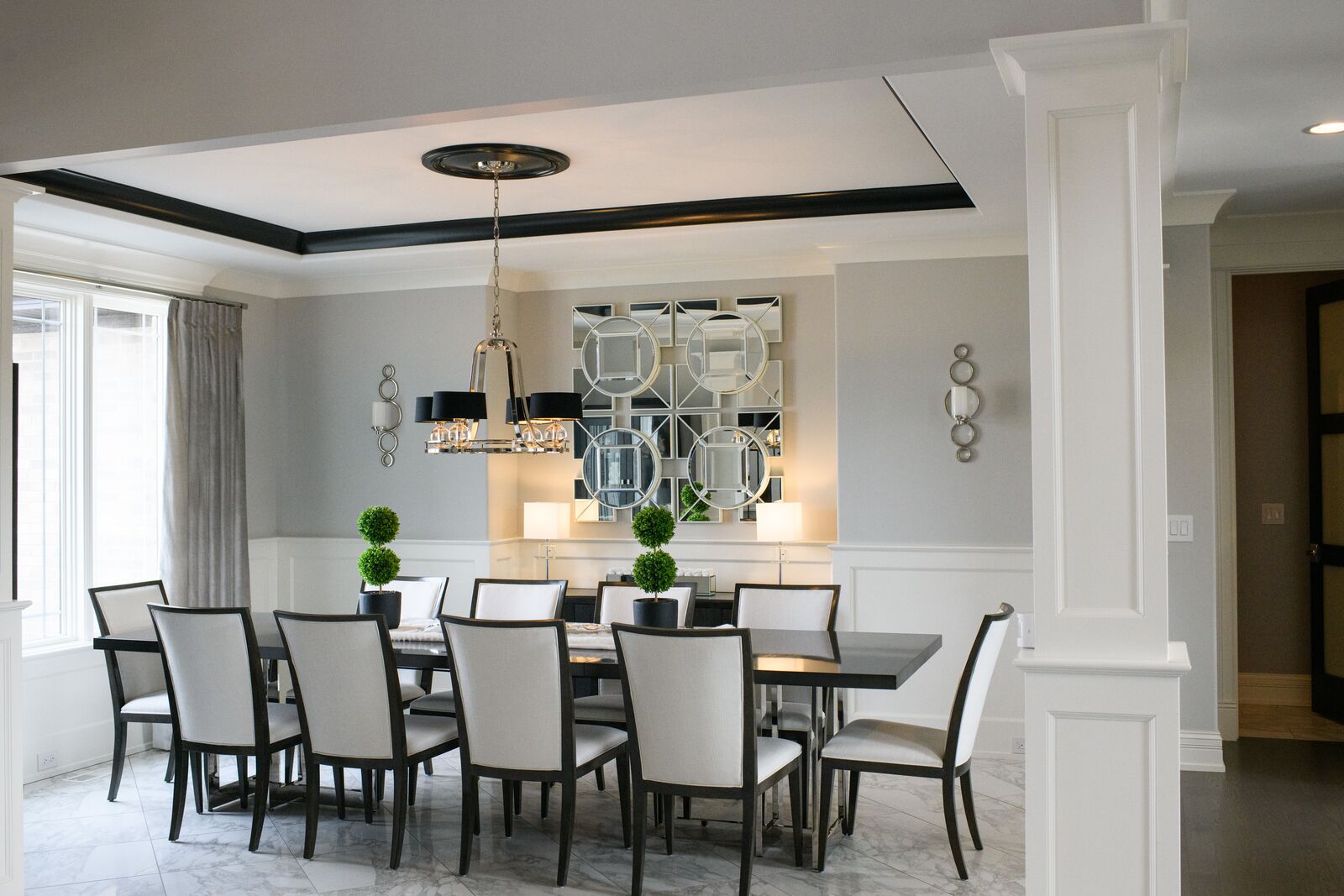 Formal dining room with a black trimmed tray ceiling, chandelier and paneled wainscoting