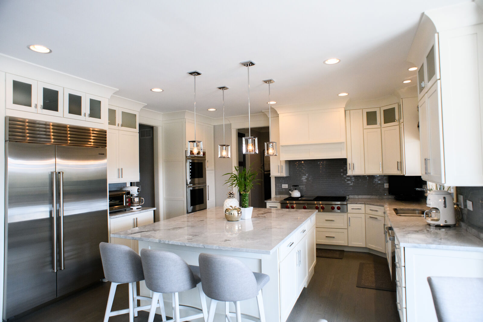 Custom kitchen with marble island, stainless appliances and a gray tile backsplash