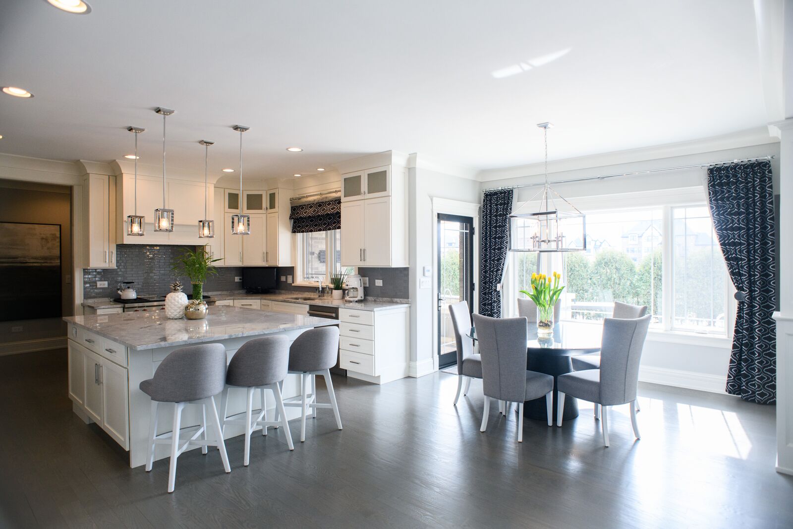 Custom kitchen opening to a breakfast area with a bay window and lantern pendant